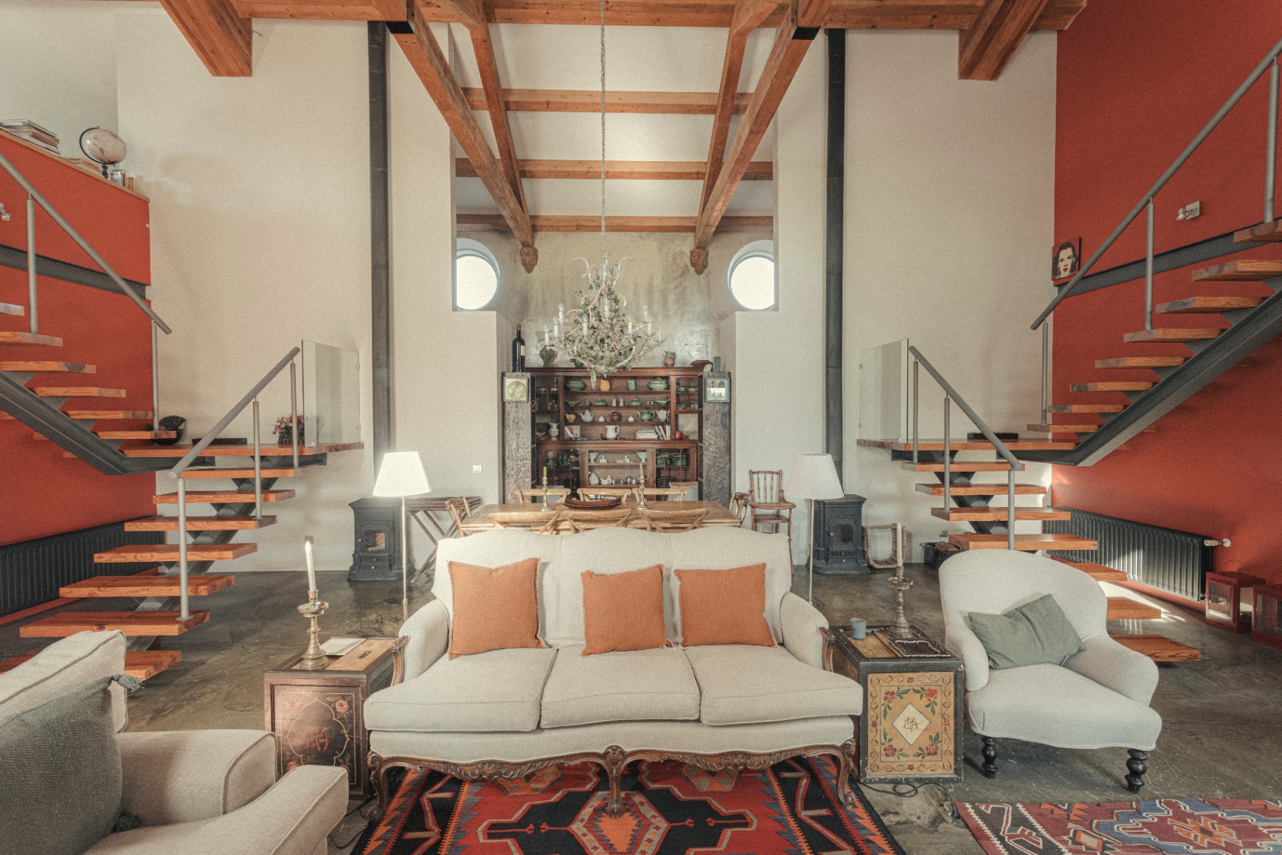 Symmetrical lounge framed by twin red staircases and a crystal chandelier