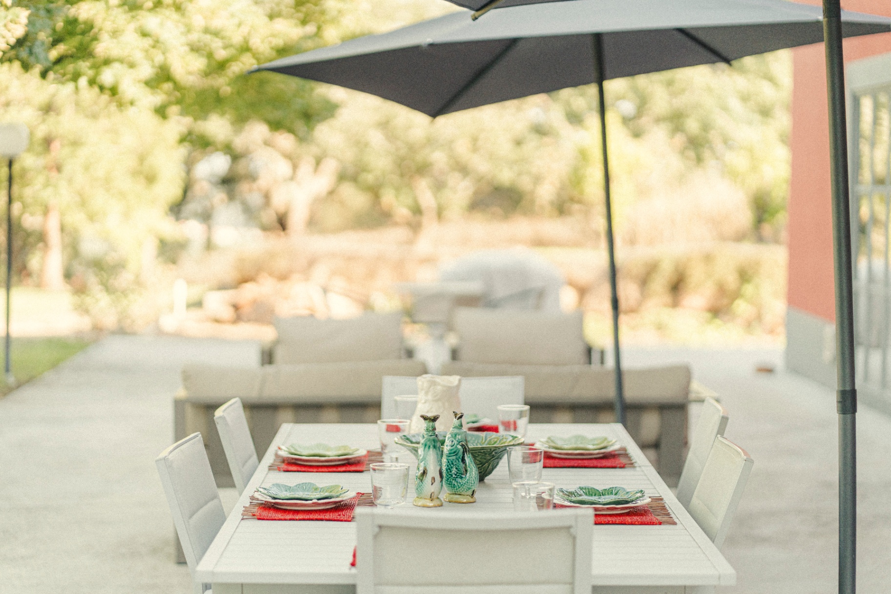 Outdoor dining table set under a parasol beside the garden