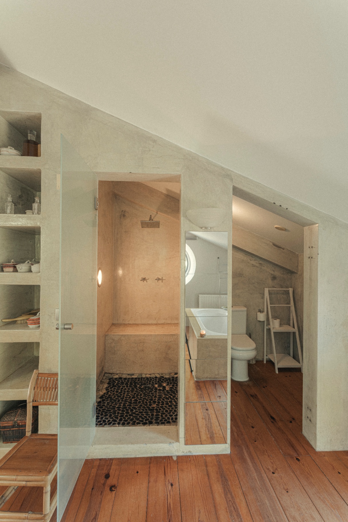 Ensuite shower and bath tucked under sloping ceilings with pebble floor
