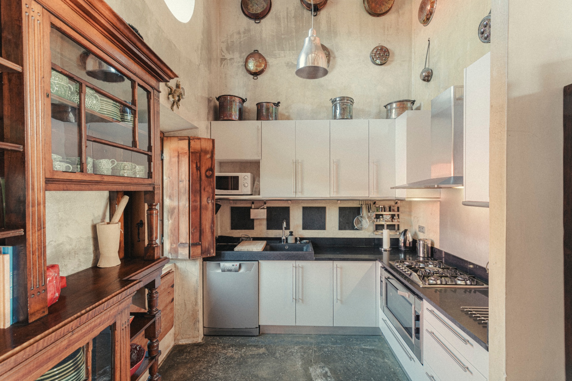 Kitchen with hanging copper pans and antique wooden dresser