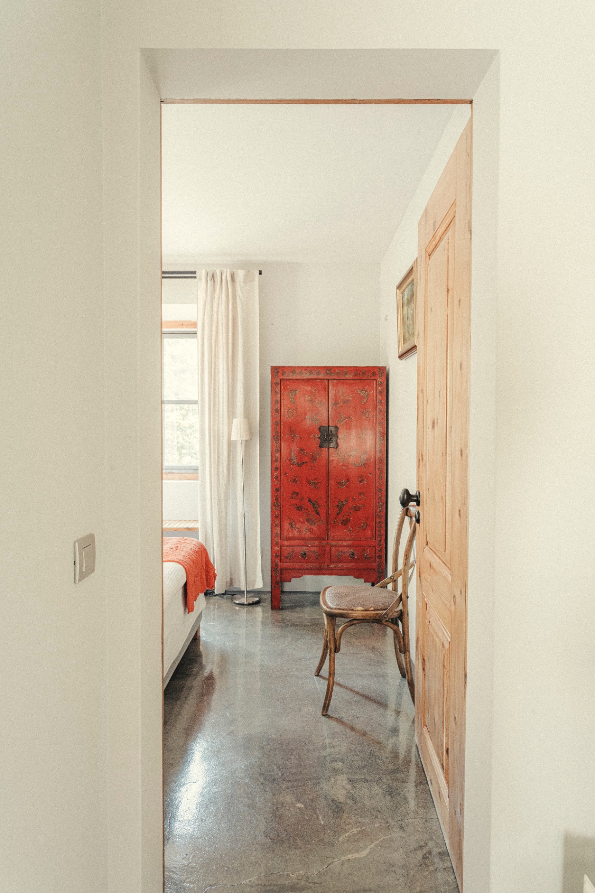 Hallway view into a bedroom with a red lacquer cabinet