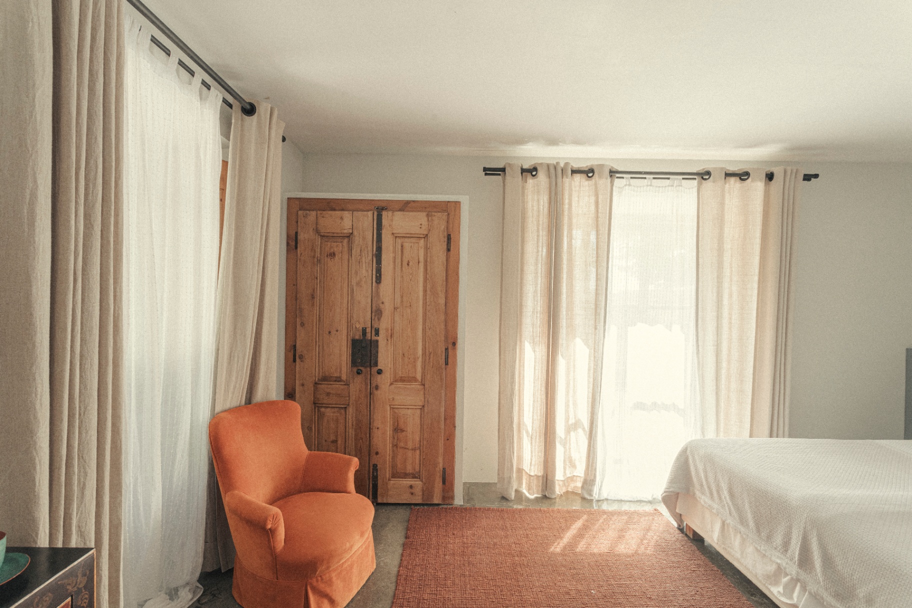 Bedroom with orange armchair and antique wooden doors