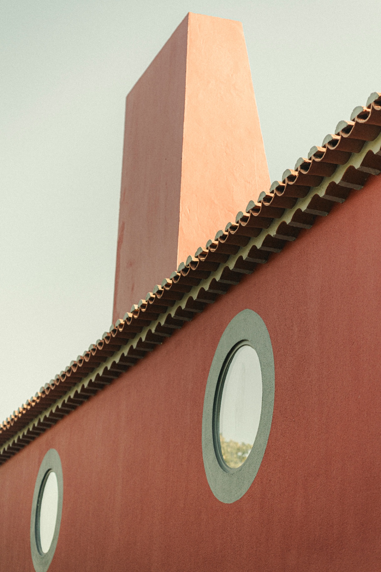 Red facade with round porthole windows and chimney against the sky
