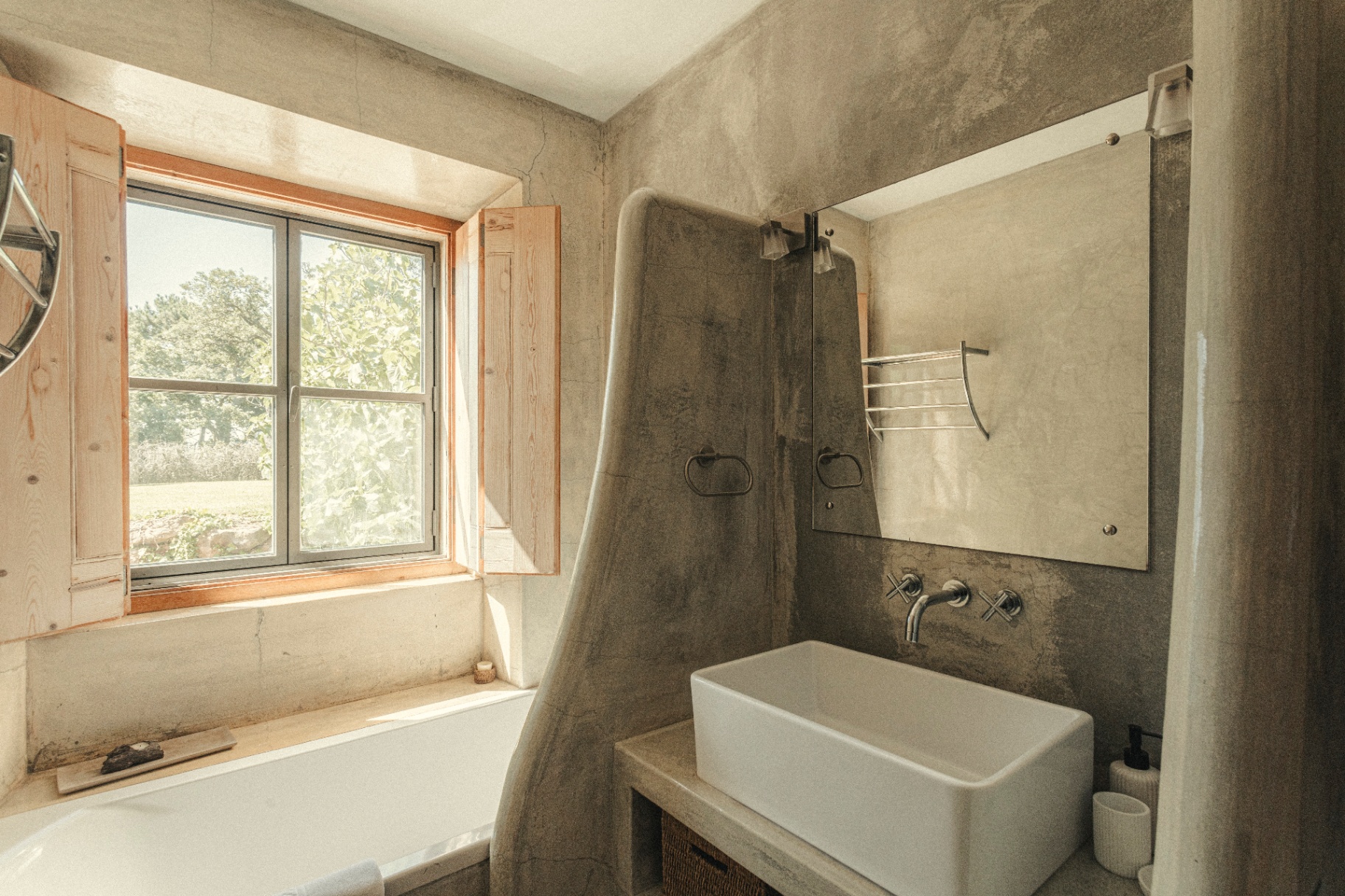 Concrete bathroom with vessel sink and shuttered window onto the garden