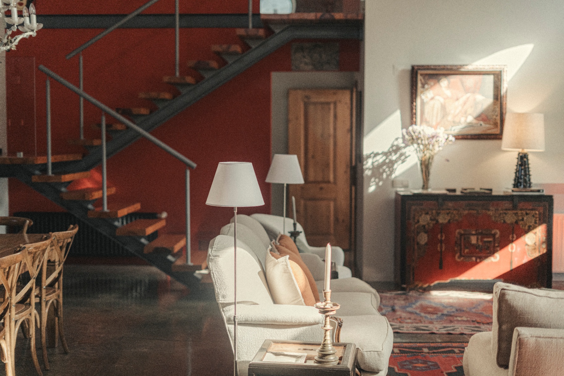 Sunlit lounge with floating staircase and antique cabinet