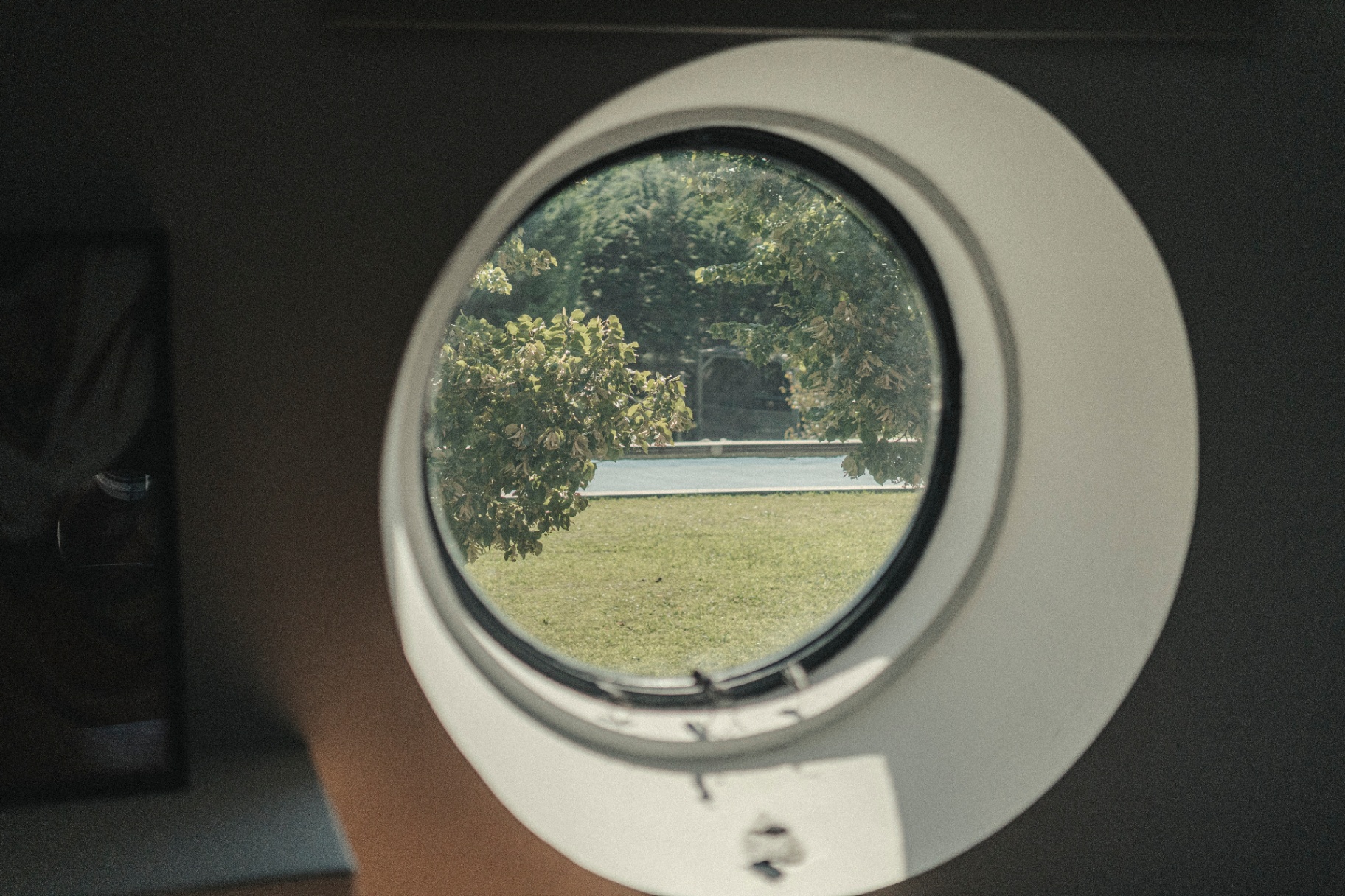 Round porthole window framing a countryside view